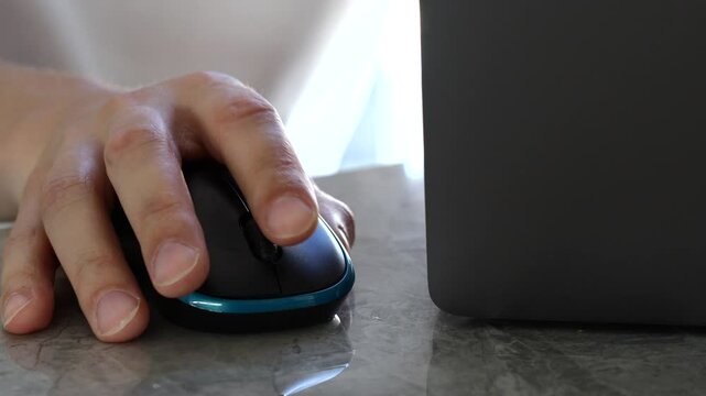 A man in a white T-shirt working on a laptop, clicking a wireless computer mouse.
A man at a computer moves a computer mouse around the table.
Freelance work
