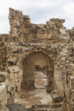 View of weathered stone archway and crumbling walls evoke ancient echoes under a soft, overcast sky, Salamis Harabeleri, Harabeleri Salamis Yolu, Cipro.