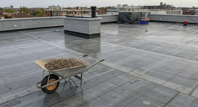 Flat roof construction wheelbarrow filled with gravel rooftop building material