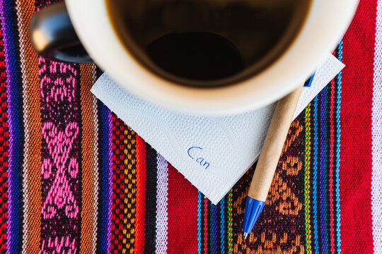 Coffee cup with a note written that says you can do it on a colorful Inca woven table