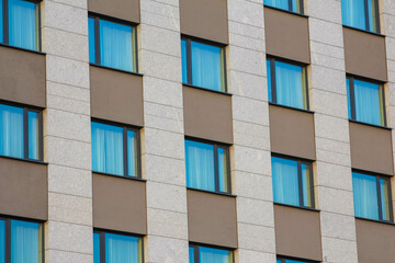 Modern residential apartment building facade with repetitive blue-framed windows and beige exterior