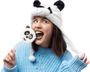Funny young girl standing with yummy panda-lollipop in her hand and a hat on his head on a pink background.