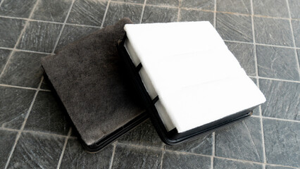 Old and new filters are stacked clearly on top of each other.  Placed on a black tiled floor.