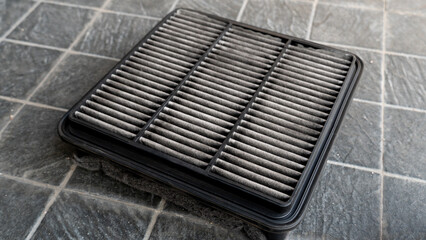 Top view of old engine air filter of car. Cloth panels are covered with black dust. Placed on a...