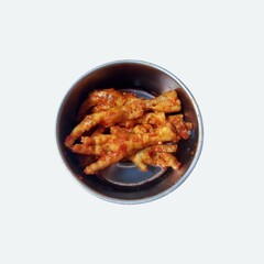 Chicken feet served with hot chili sauce or firecracker feet in an iron bowl. Traditional food
