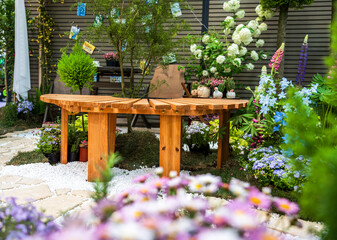 Tranquil Garden Retreat With Wooden Table Surrounded by Colorful Blooms and Greenery