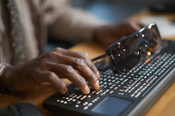 Rear view of person with blindness disability using computer keyboard and braille display or braille terminal a technology assistive device for persons with visual impairment