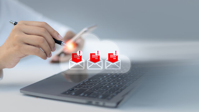 Close-up of a hand using a smartphone and laptop with warning email icons, representing phishing alert, email scam detection, cybersecurity, and digital threat protection in cloud systems.