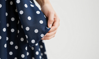 Close-up of a woman’s hand holding the edge of a soft polka-dotted dress  Generative AI