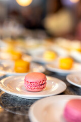 Yellow and red sweet macaroons on the table on a white plate. Luxurious baked cakes at a celebration
