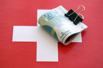 Swiss franc banknotes and flag. The francs money bills lies on flag in big amount