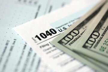 Hundred dollar bills and 1040 individual income tax return form blank close up
