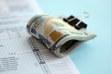 Big amount of United States USD dollar bills on table with 1040 tax return form