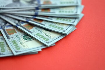 Big amount of United States hundred dollar bills on red background