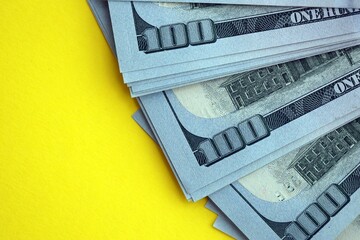 Big amount of United States hundred dollar bills on yellow background