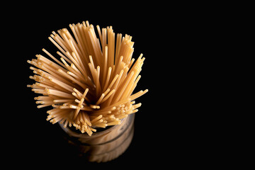 Overhead perspective of a glass jar filled with uncooked spaghetti strands, creating an interesting...