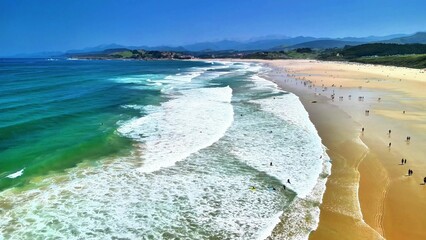 A stunning view of a vibrant beach where waves crash on the shoreline as people enjoy the beautiful...