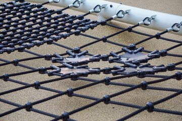 Modern playground climbing net structure and bike rack in a green city park at sunset. Urban recreational area for children and adults