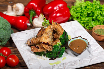The plate features a serving of fried fish pieces, garnished with microgreens and drizzled with a dark sauce. The fish is accompanied by steamed broccoli, sprinkled with grated cheese and sesame seeds