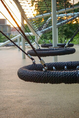 Modern playground with yellow slide and black tunnel tube structure in urban park. Sunny day, city skyscrapers in background. Children's outdoor play area