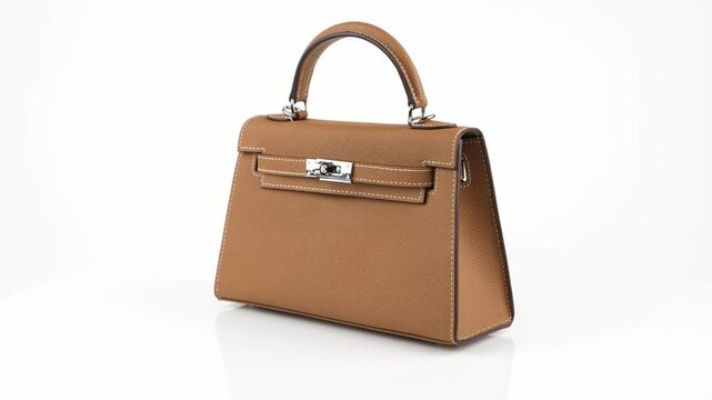 Seamless 360-degree loop of a caramel brown leather handbag with structured design and silver clasp, isolated on white background. Ideal for showcasing fashion accessories in 4K.