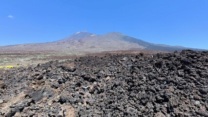 An expansive and breathtaking volcanic landscape showcasing rough and rugged lava rocks along with a towering volcano
