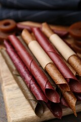 Tasty fruit leather rolls on wooden table, closeup