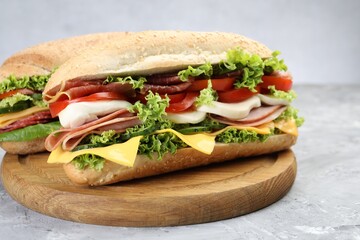 Tasty baguette sandwiches with ham, cheese and vegetables on grey textured table, closeup