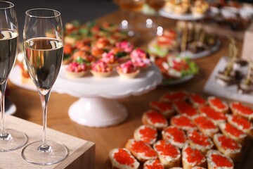 Buffet menu. Glasses of sparkling wine and tasty appetizers on table, closeup