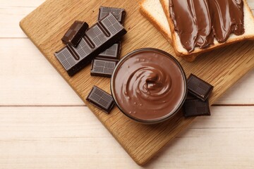 Tasty chocolate butter, pieces and sandwiches on wooden table, top view