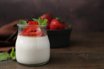 Tasty panna cotta with caramel, strawberries and mint on wooden table, closeup. Space for text