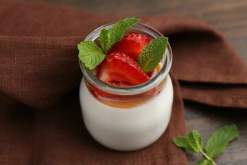 Tasty panna cotta with caramel, strawberries and mint on table, closeup