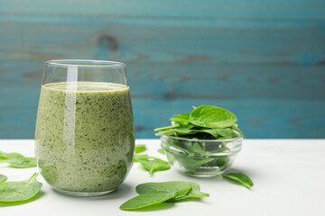 Tasty smoothie and spinach leaves on white marble table, closeup. Space for text
