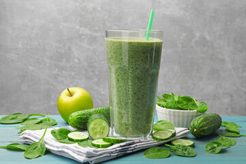 Tasty spinach smoothie and ingredients on light blue wooden table, closeup