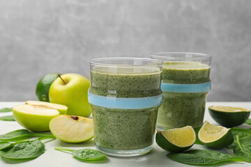 Tasty smoothie and spinach leaves on white table, closeup