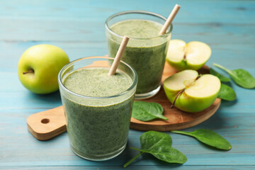 Tasty spinach smoothie and ingredients on light blue wooden table, closeup