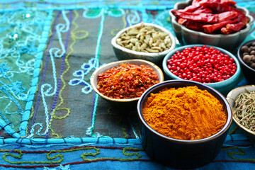 Many different aromatic spices in bowls on table with cloth, closeup. Space for text