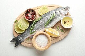 Fresh raw seabass with spices on white table, top view. Fish and seafood delicacies