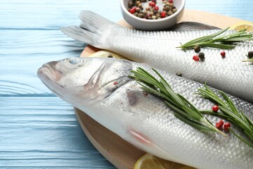 Fresh raw seabass with spices on blue wooden table, closeup. Fish and seafood delicacies