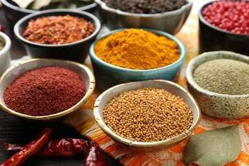 Different aromatic spices on orange tablecloth, closeup