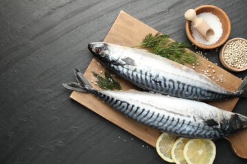 Seafood delicacies. Fresh raw mackerels and spices on black table, flat lay. Space for text