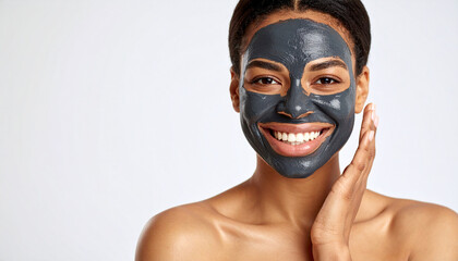 Smiling woman with charcoal face mask applying skincare treatment, showing healthy glowing skin and natural beauty with clean space on left side
