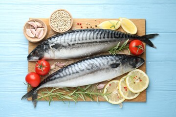 Fresh raw mackerels and spices on light blue wooden table, flat lay. Seafood delicacies