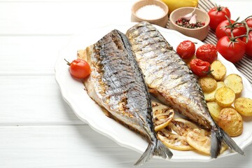 Homemade seafood dish. Tasty roasted mackerels with spices, tomatoes and potatoes on white wooden...