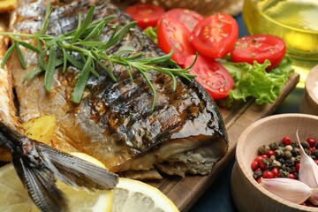 Tasty roasted mackerels served with spices and vegetables on table, closeup. Homemade seafood dish