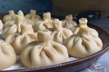 Close-up presentation of uncooked khinkali, Georgian dumplings, showcases their light beige color...