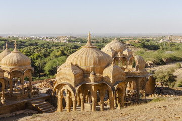 View of intricately carved sandstone cenotaphs rise majestically from the arid landscape, a testament to history and artistry, Jaisalmer, Rajasthan, India.