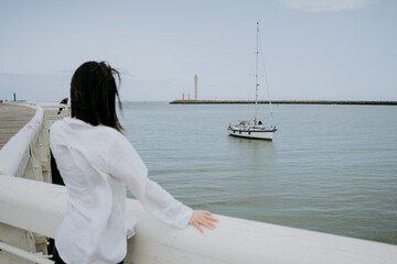 Obraz premium The girl is standing and looking at the passing boat.