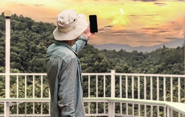 Tourists use their phones to take pictures of the sunset.