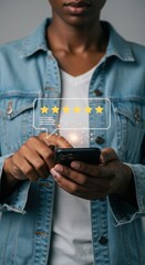 Person holding smartphone with five-star rating. Digital feedback interaction with yellow stars. Customer review concept with denim jacket.
